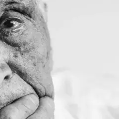 Nahaufnahme eines älteren Mannes mit Falten im Gesicht. Sein Blick wirkt nachdenklich, fast ein Blick ins Leere, der an Demenz erinnern kann.